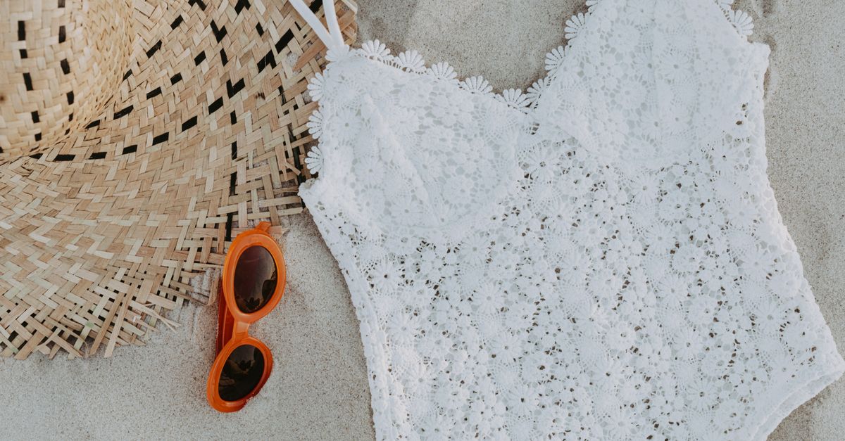 Tween swimwear and sun hat laid out on sand